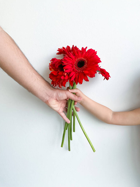 niño pequeño le da a su padre un ramo de flores sobre fondo blanco. Día del Padre. concepto de tarjeta de vacaciones con lugar para el texto - Foto, imagen