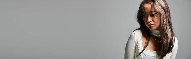 banner de menina cobrindo rosto com cabelo e olhando para o lado contra fundo cinza - Foto, Imagem