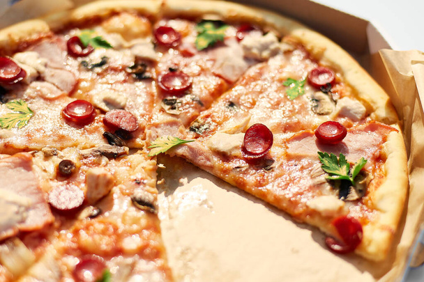 Tuoreesta pizzasta, jossa on viipaloituja tomaatteja, juustoa, sieniä ja yrttejä, puuttuu kaksi viipaletta, mikä viittaa jaettuun ateriaan ulkona piknikillä.. - Valokuva, kuva