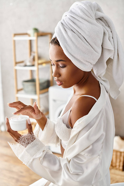 Afrikai amerikai nő afro fonat kezében egy üveg krém a modern fürdőszobában, elősegítve a szépség és higiénia. - Fotó, kép