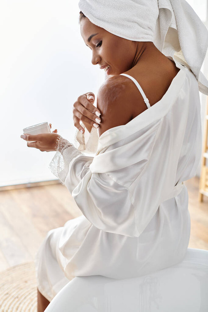 Αφροαμερικανή γυναίκα με λευκό φόρεμα απολαμβάνοντας κρέμα στο σώμα της - Φωτογραφία, εικόνα
