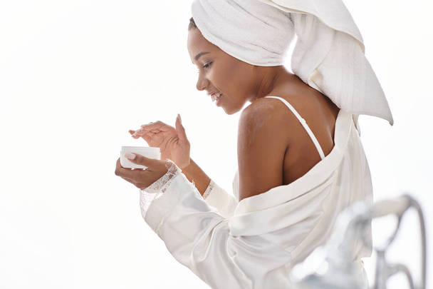 Афроамериканка завернутая в полотенце после ванны, олицетворяющая красоту и гигиену. - Фото, изображение