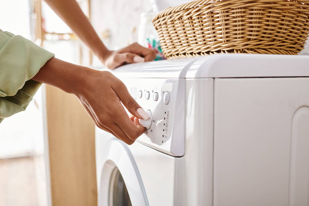 Afrikalı Amerikalı bir kadın banyodaki çamaşır makinesine kurutucu yüklüyor.. - Fotoğraf, Görsel