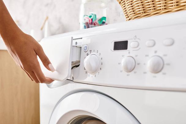 Africano mulher americana com tranças afro fazendo lavanderia no banheiro, pressionando botão na máquina de lavar roupa. - Foto, Imagem