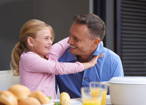 Οικογένεια, πατέρας και κόρη αγκαλιάζονται για μεσημεριανό γεύμα στο τραπέζι της τραπεζαρίας στο σπίτι μαζί για υγεία, διατροφή ή διατροφή. Φαγητό, χαμόγελο ή χαρούμενος με τον άνθρωπο γονέα και το νεαρό κορίτσι στο διαμέρισμα για μεσημεριανό γεύμα. - Φωτογραφία, εικόνα