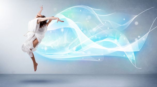 Cute teenager jumping with abstract blue scarf around her - Foto, Imagen