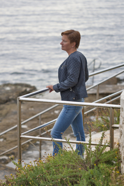 Mujer caucásica de mediana edad mirando pensativamente hacia el mar
 - Foto, imagen