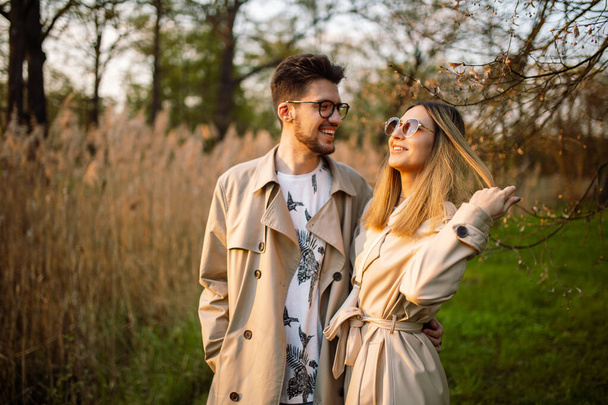 Portré egy boldog szerető párról egy tavaszi parkban, akik gyönyörű időjárást és naplementét élveznek. Pihenés, ifjúság, szerelem, életmód magány a természettel - Fotó, kép