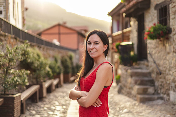 Portrait of young hispanic woman standing with crossed arms. She is in a rural town during sunset. High quality photo - Photo, Image
