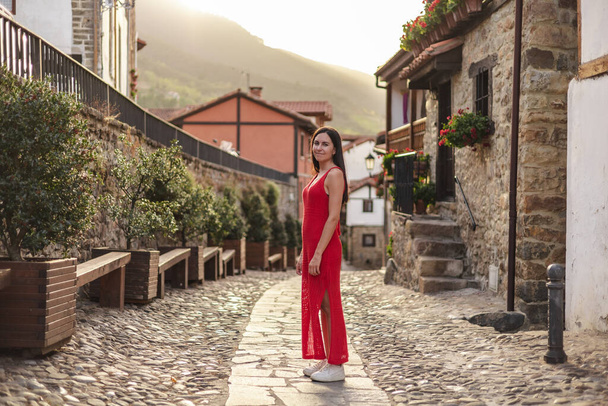 Retrato de jovem hispânica de pé com vestido vermelho. Ela está em uma cidade rural durante o pôr do sol. Foto de alta qualidade - Foto, Imagem
