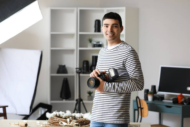 Junger männlicher Fotograf mit professioneller Kamera im Studio - Foto, Bild
