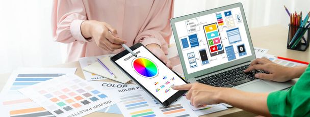 Η κομμένη εικόνα της ομάδας εσωτερικών σχεδιαστών παρουσιάζει το χρώμα χρησιμοποιώντας την παλέτα χρωμάτων ενώ το lap-top επιδεικνύει τα σχέδια UI και UX για την εφαρμογή και την ιστοσελίδα κινητών. Δημιουργικός σχεδιασμός και επιχειρηματική ιδέα. Ποικιλία. - Φωτογραφία, εικόνα