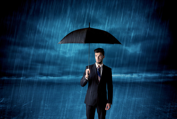 傘を差して雨の中に立つサラリーマン - 写真・画像