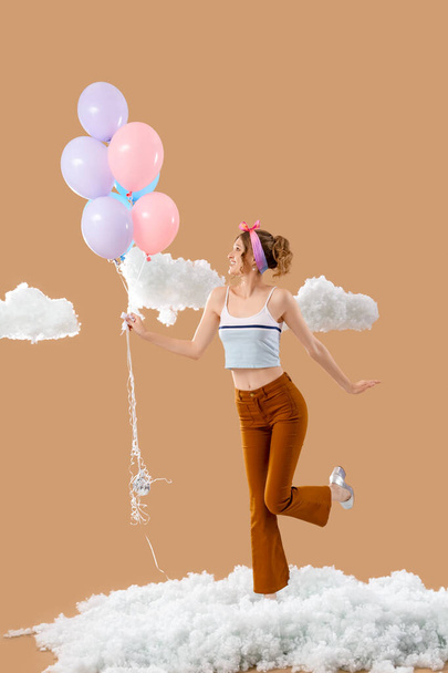 Молода жінка з повітряними кулями та білими хмарами на бежевому фоні - Фото, зображення