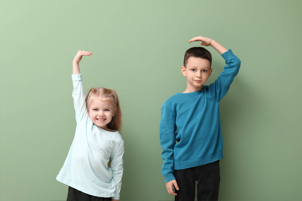 Crianças pequenas bonitos medindo altura no fundo verde - Foto, Imagem