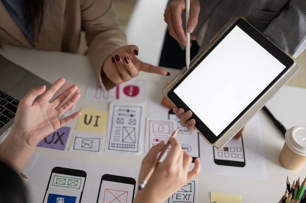 A megbeszélésen egy kreatív UX UI grafikus csapat közeli képe is jelen van, akik munkáról beszélgetnek és együtt nézik a digitális táblagépet. egy fehér képernyős digitális tabletta mockup - Fotó, kép