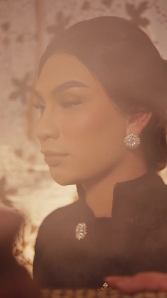 Elegantní žena s jemným make-up v černém oblečení, retro styl portrét s teplými tóny a květinové pozadí uvnitř místnosti - Záběry, video