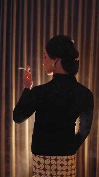 Элегантная женщина в силуэте курит на фоне занавеса, угрюмое освещение ночью - Кадры, видео