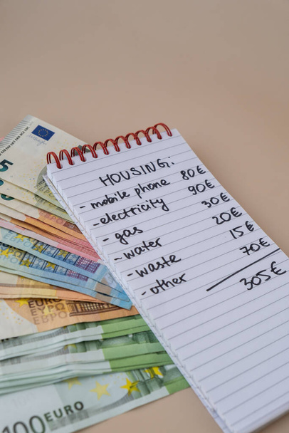 Euro Bargeld mit Notizbuch handgeschriebene Wohnkosten. Rechnungen für Strom, Gas, Wasser zählen. Konzept für effizienten Konsum und Wirtschaftlichkeit. Ausgabegewohnheiten - Foto, Bild