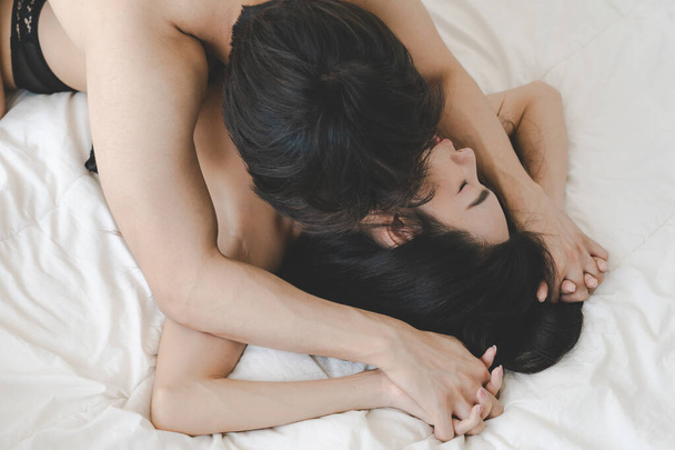 Foto lateral de casal asiático no quarto. Casal apaixonado atraente está fazendo sexo na cama. Dia dos Namorados. sentindo amor e felizes juntos - Foto, Imagem