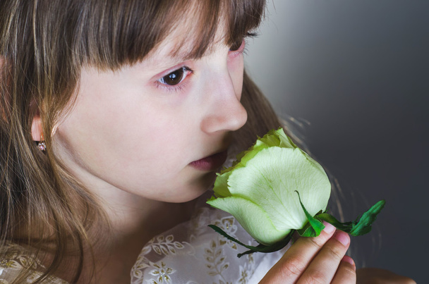 Κορίτσι μυρίζοντας ένα όμορφο λευκό τριαντάφυλλο - Φωτογραφία, εικόνα