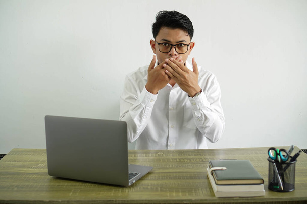 jeune homme d'affaires asiatique dans un lieu de travail couvrant la bouche avec les mains, porter chemise blanche avec des lunettes isolées - Photo, image