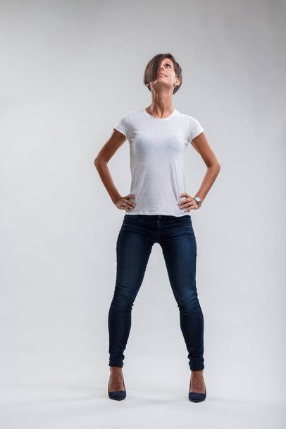 Женщина в повседневной шикарной одежде смотрит вверх, воплощая уверенность и решимость в своей позиции - Фото, изображение