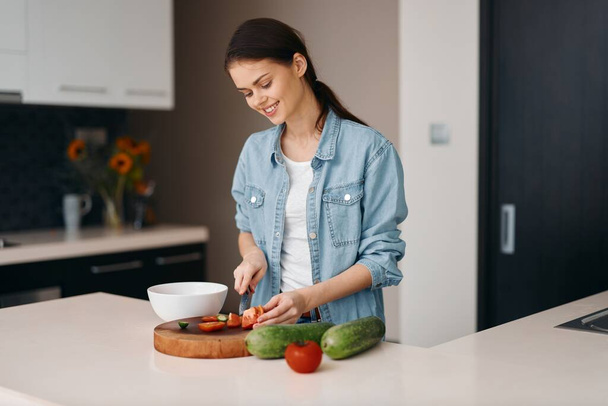健康的なライフスタイル:ホワイトキッチンで新鮮なベジタリアンサラダを作る若い女性クック - 写真・画像