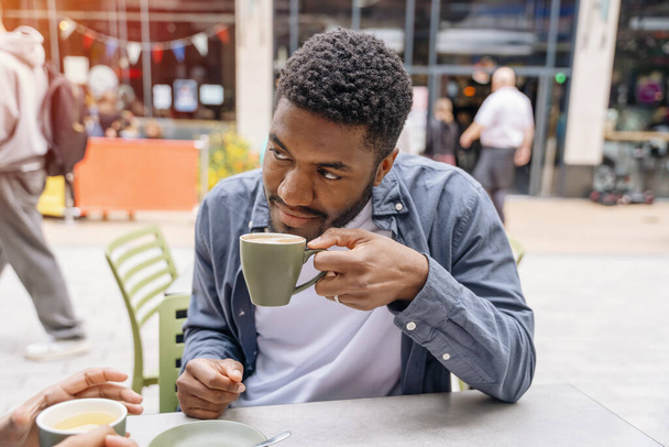 koppel zit in een café op straat en drinkt thee en koffie als onderdeel van het urban lifestyle concept - Foto, afbeelding