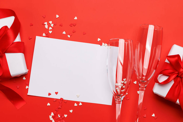 Σαμπάνια και δώρο: Γιορταστικό δίδυμο σε κόκκινο φόντο με χώρο κειμένου. Ημέρα του Αγίου Βαλεντίνου ευχετήρια κάρτα - Φωτογραφία, εικόνα