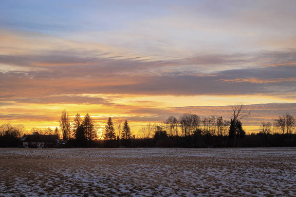 Barevný východ slunce se zářícími rudými mraky za zimního dne nad loukami a lesy Siebenbrunnu, nejmenší čtvrti města Augsburg - Fotografie, Obrázek