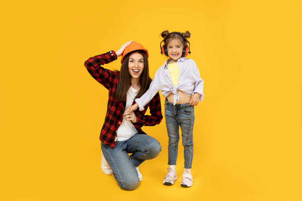 Mother and daughter in accessories for construction, on a yellow background. - Photo, Image