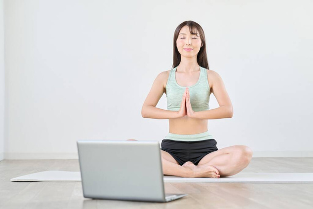 Een vrouw mediteren terwijl ze naar een computer kijkt - Foto, afbeelding