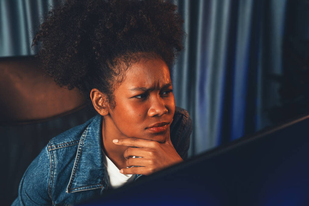 Giovane donna creatrice afroamericana dal volto serio, che pensa attentamente e guarda il documento finale del progetto su laptop per pianificare la sequenza successiva. Concetto di lavoro in casa pulito. Tastificatore. - Foto, immagini