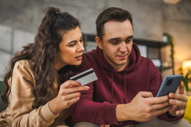 カップル慎重な男と女性の夫と妻またはボーイフレンドやガールフレンドは,ラップトップコンピュータとクレジットカードのショッピングをオンラインで購入するか,家の人々から支払い予約電子商取引を行う - 写真・画像