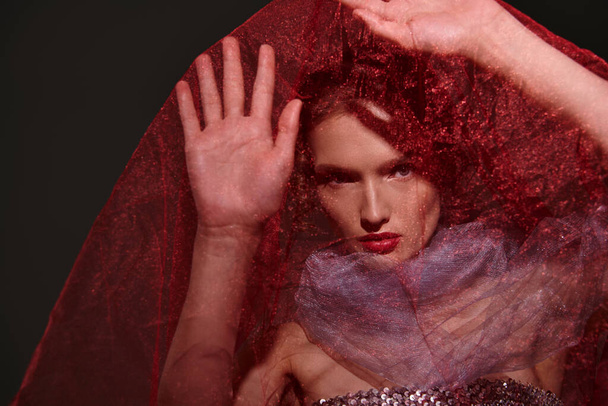 Молодая женщина с яркими рыжими волосами элегантно позирует в студии, с вуалью на голове. - Фото, изображение