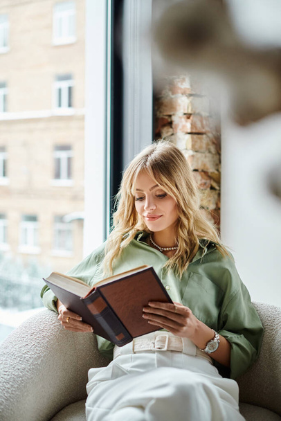 Egy nő, aki otthon ül egy székben, lefoglal egy könyv olvasása.. - Fotó, kép