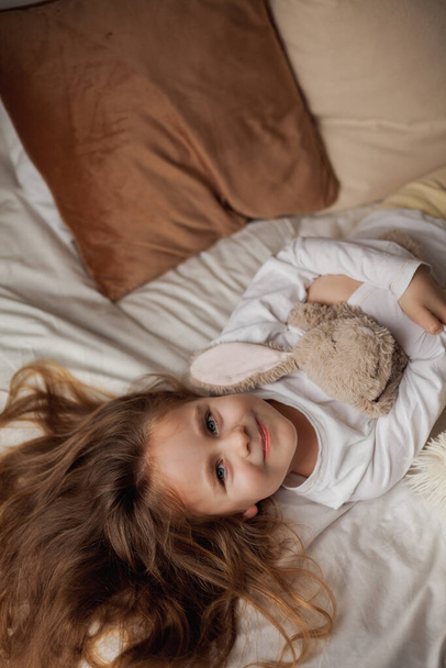 Entzückendes glückliches Kind. Porträt eines kleinen lächelnden süßen Mädchens mit blauen Augen und langen Haaren. - Foto, Bild