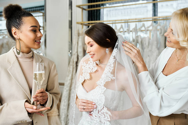 Дві жінки, одна молода наречена в білій сукні, а інша її мати, стоять біля стійки суконь у весільному салоні. - Фото, зображення