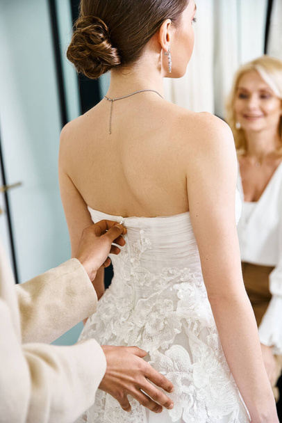 A young, brunette bride in a white wedding dress prepares for her big day in a serene bridal salon. - Photo, Image