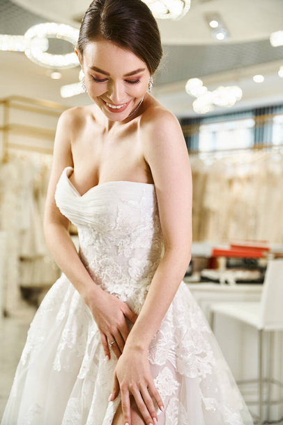 Uma jovem noiva morena está sorrindo feliz em um vestido branco dentro de um salão de casamento. - Foto, Imagem