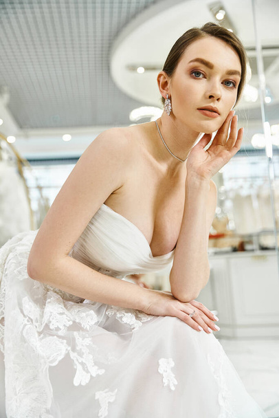 A young brunette bride in a white dress posing regally for a picture in a wedding salon. - Foto, afbeelding