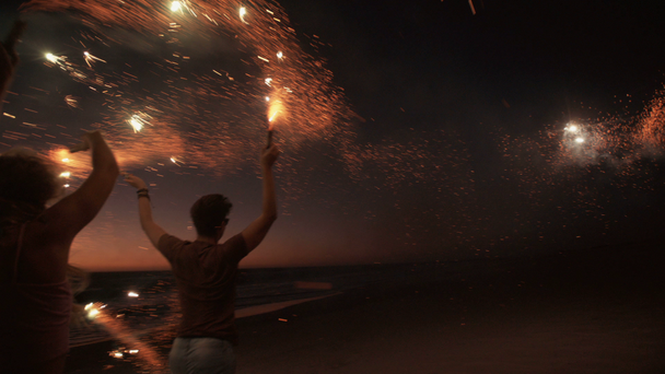 Amigos correndo em uma praia com fogos de artifício
 - Filmagem, Vídeo