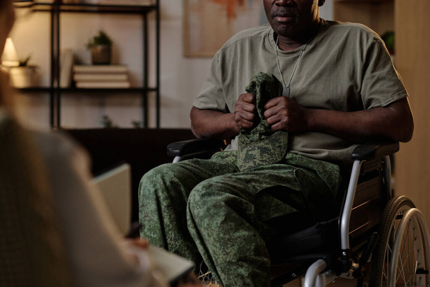 Ancien combattant de la guerre noire avec le stress post-traumatique tenant fermement son uniforme coiffure à la session avec psychologue - Photo, image