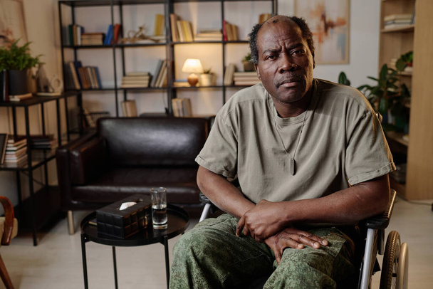 Veterano de guerra negra grave com deficiência sentado no escritório do psicólogo e olhando para a câmera - Foto, Imagem