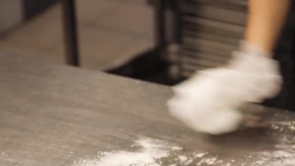 Seguindo Close Up tiro de mulher varrendo farinha fora de superfície de mesa de alumínio na cozinha do restaurante - Filmagem, Vídeo