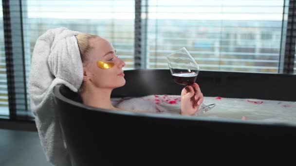 スパリラックス。 赤ワインでグラスを持って入浴している女性. 家でトイレでリラックスする女の子. かわいい女性がお風呂でワインを飲んでいます. ストレス解消。 一生懸命働いた後の休息 - 映像、動画