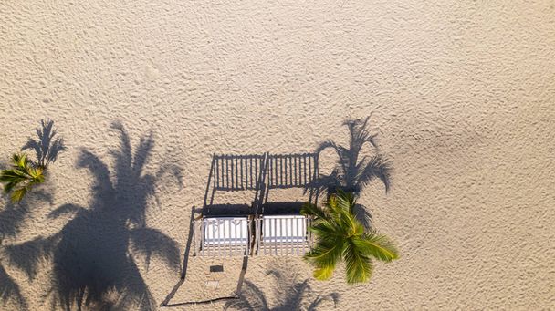 Vista dall'alto verso il basso di un gazebo in legno sulla spiaggia sabbiosa con ombre di palma. - Foto, immagini