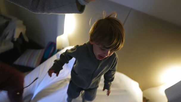 Family Joy on Vacation - Parents and Son Bouncing on Hotel Bed - Photo, Image