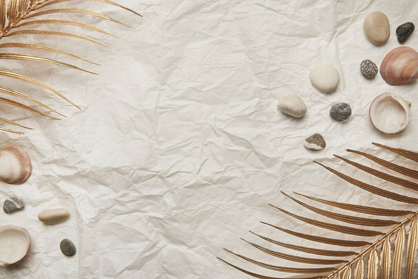 Plaj taşları, çakıl taşları, buruşuk kağıt üzerinde altın palmiye yaz arkaplanı. Boşluğu kopyala. - Fotoğraf, Görsel